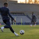 Un joueur des Bleus s'échauffe à l'entraînement, ballon au pied, sous le regard du staff.