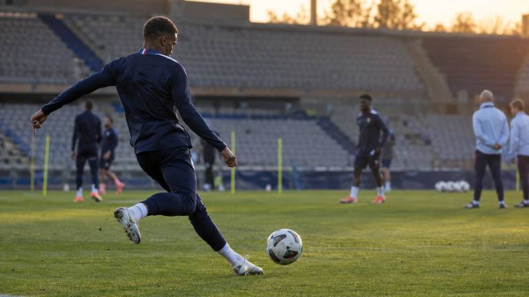 Un joueur des Bleus s'échauffe à l'entraînement, ballon au pied, sous le regard du staff.