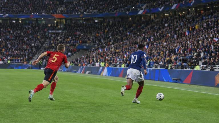 Joaquín Seys defiende ante un atacante francés durante un partido de la Liga de Naciones entre Bélgica y Francia, vista lateral, con el estadio completo al fondo…