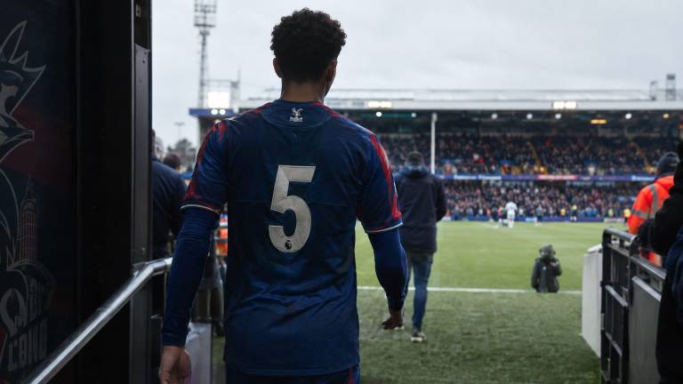 Un jeune joueur de Crystal Palace, vu de dos, entre sur la pelouse d'un stade anglais.