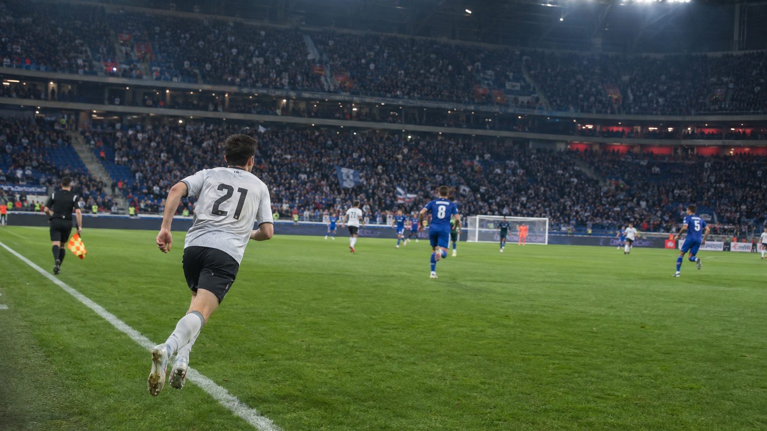 Latéral n°21 courant le long de la ligne de touche lors d’un match OL-OM sous les projecteurs, foule en tribune