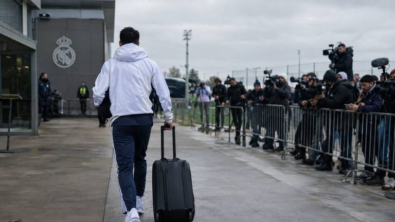 Un joueur du Real Madrid quitte le centre d’entraînement, valise à la main, entouré de médias.