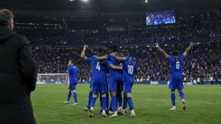 Joueurs de l’équipe de France célébrant une victoire sur la pelouse du Stade de France, public en arrière-plan.